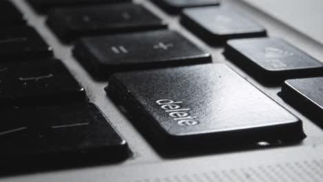 close-up of finger pressing "delete" key on laptop keyboard