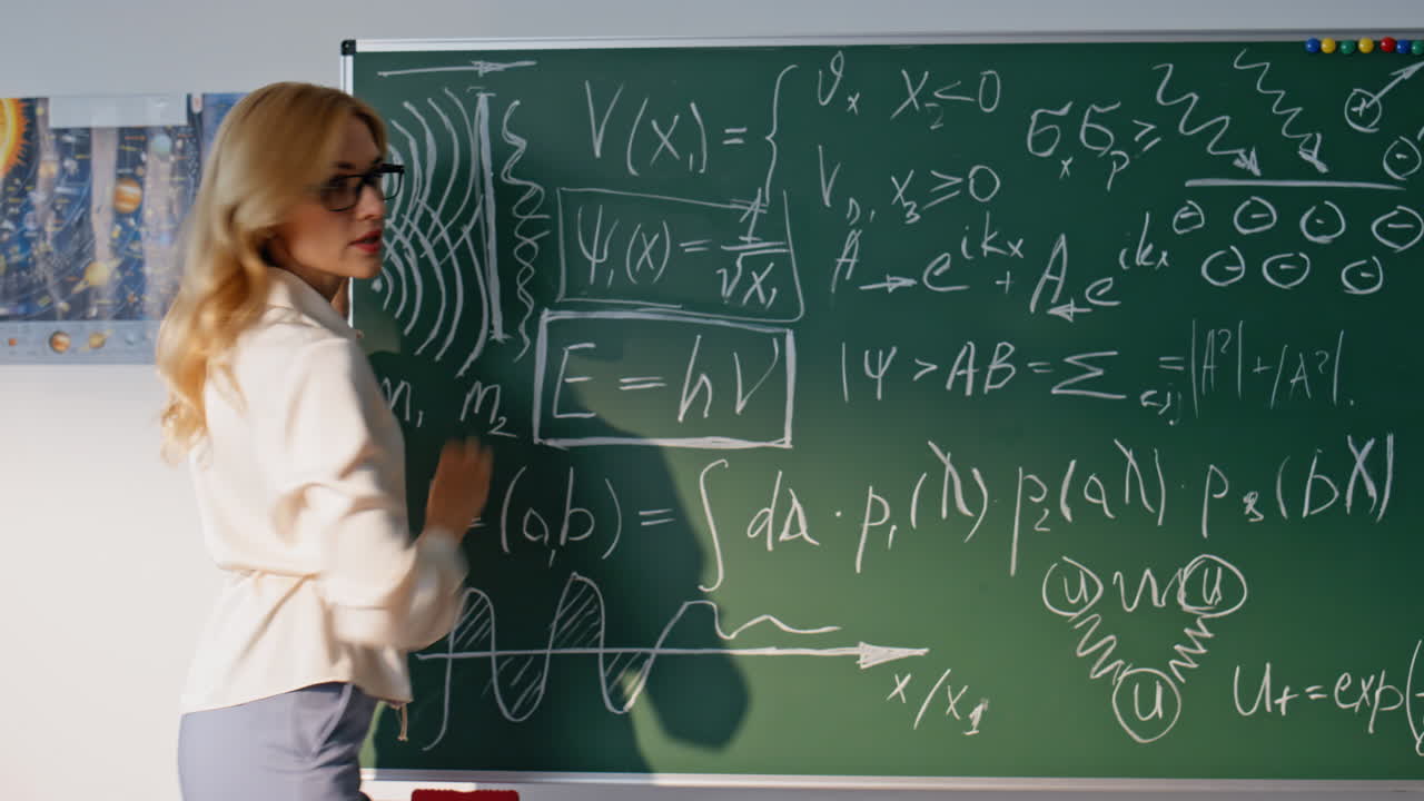 Žena vyučující fyziku ve škole píše data na tabuli ve třídě, detailní záběr