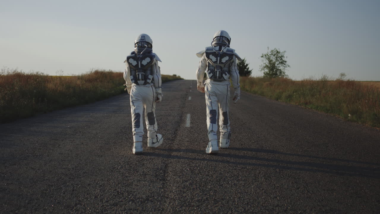 dos niños con trajes de astronautas caminando por un camino de campo.