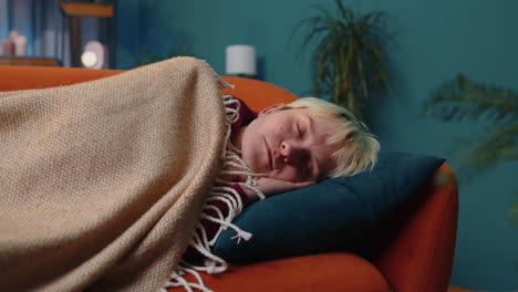 mujer joven rubia cansada acostada en la cama tomando un descanso en casa, durmiendo quedándose dormida en el sofá