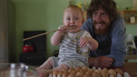 portrait of happy caucasian father and son looking at camera in kitchen