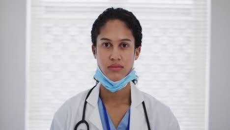 portrait of mixed race female doctor putting a face mask on