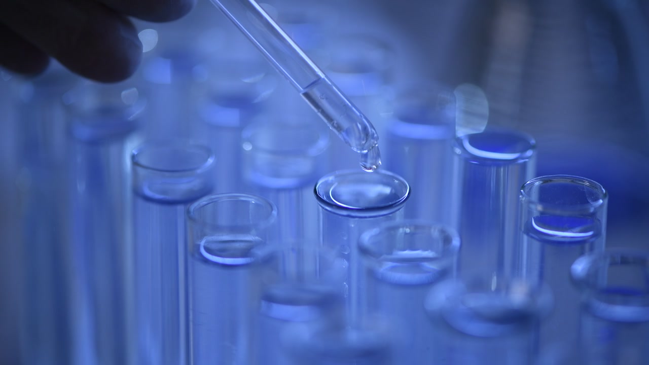 Close-up of Pipette Dropping Liquid into Test Tubes