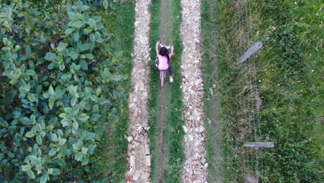 toma aérea de seguimiento de una niña montando su bicicleta por una carretera de campo
