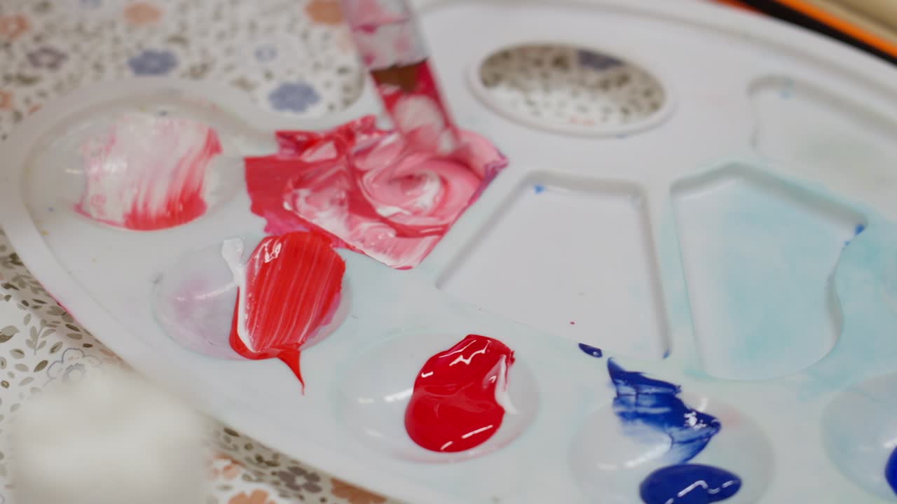 Close-up of paint palette with vibrant colors being mixed using a knife