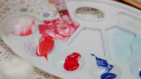 close-up of paint palette with vibrant colors being mixed using a knife