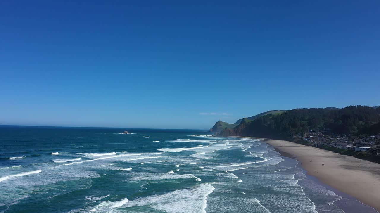 Wide establishing aerial shot of waves crashing onto the beach at Lincoln City, Oregon