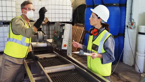 Workers-inspecting-olive-in-machine-in-factory