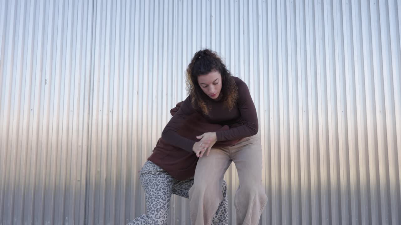 Young women dancing a choreography in front of a metal wall