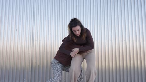 young women dancing a choreography in front of a metal wall