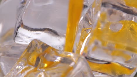 orange juice pouring over ice cubes