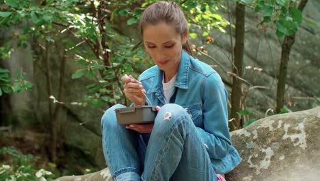 joven mochilero comiendo en el bosque