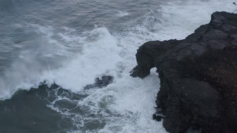 toma aérea de arriba hacia abajo de poderosas olas oceánicas que se estrellan contra las rocas de islandia