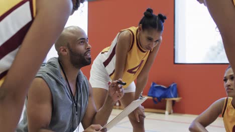 happy diverse female basketball team training with male coach in indoor court, in slow motion