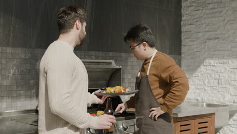 a young guy and his friend talking while having a barbecue