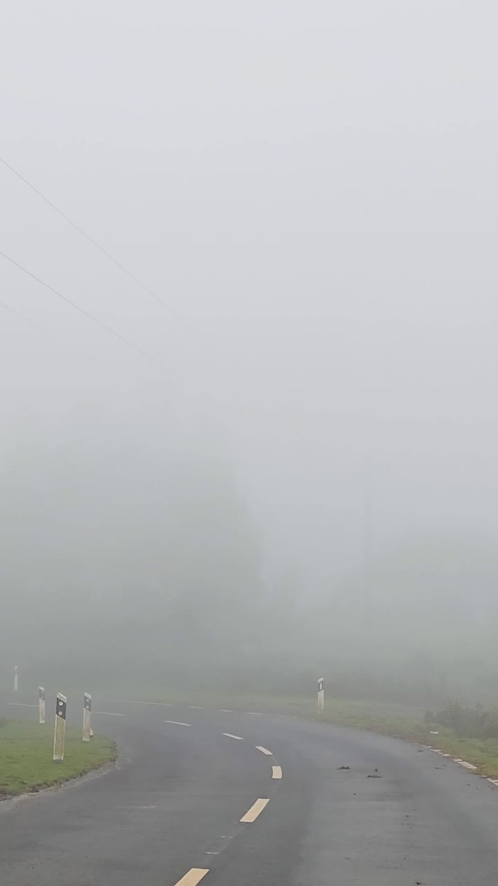 Densa niebla cubriendo una carretera de montaña durante el clima tormentoso en Madeira con baja visibilidad, viento fuerte, atmósfera lúgubre y condiciones dramáticas creando imágenes de viaje cinematográficas y tensas.