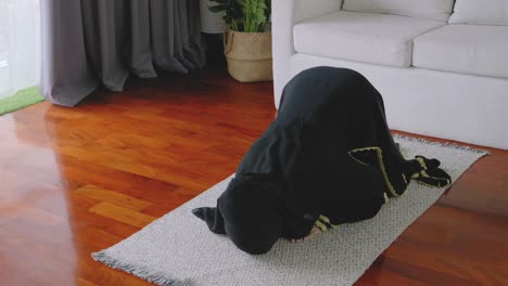asian young woman muslim prayers bow to pray for blessings in the living room, belief in islam muslims pray at home daily as a blessing for themselves and their family