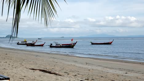 fishing boats moored along a windswept beach during the day in southern thailand