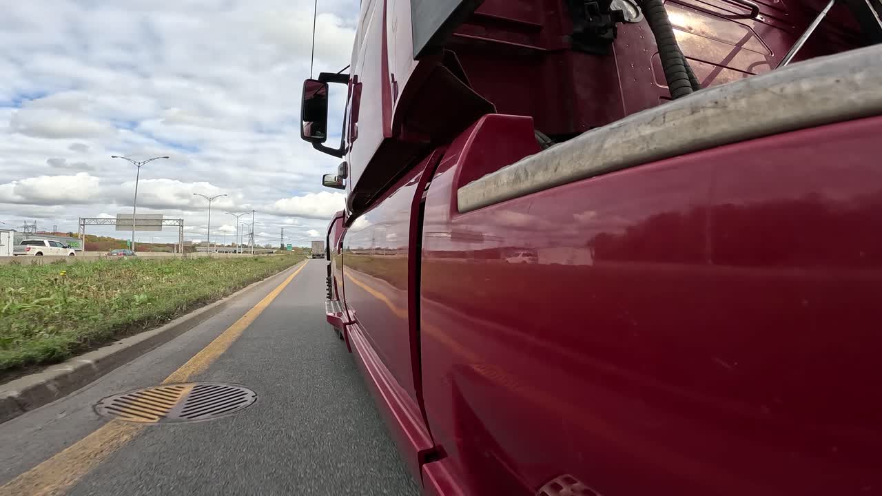 POV shot of a RED semi truck driving on the freeway, taking an exit ramp on a cloudy day