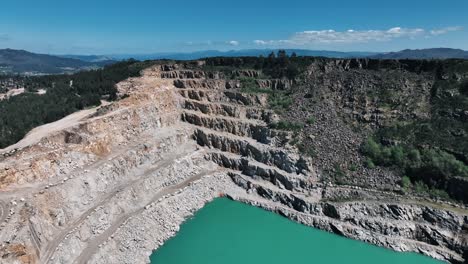 expansive aerial shot of a stepped quarry landscape with turquoise lake