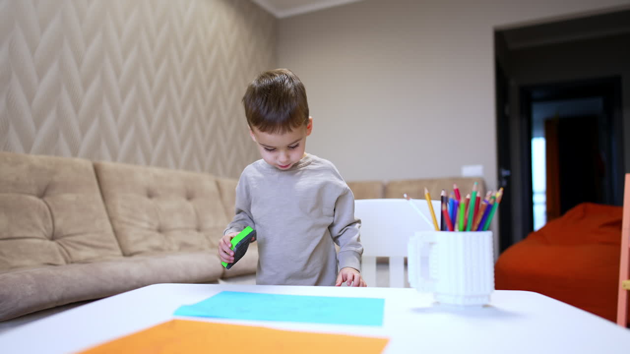 Child creating at home. A child is focused on crafting, using colorful paper and a tool on a table in a cozy indoor setting