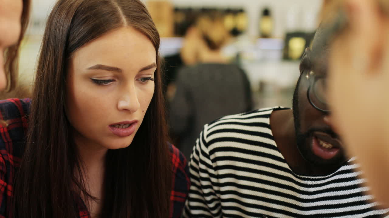 다민족 동료가 문서를 읽고 카페 테이블에 앉아 커피를 마시며 이야기하는 모습