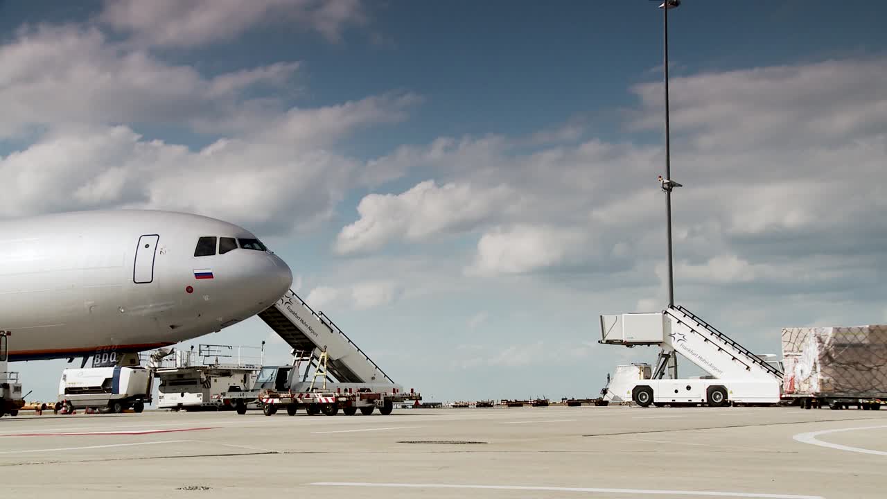 avión comercial en la puerta con equipo de apoyo en tierra y cielo nublado