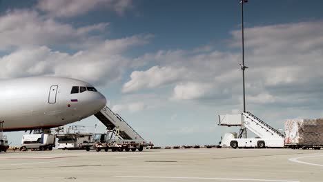 commercial airplane at the gate with ground support equipment and cloudy sky