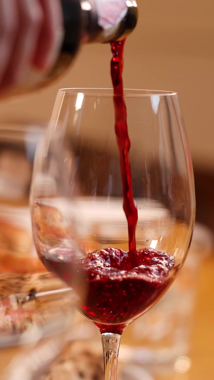 Primo piano di vino rosso che viene versato dalla bottiglia nel bicchiere su un tavolo di ristorante