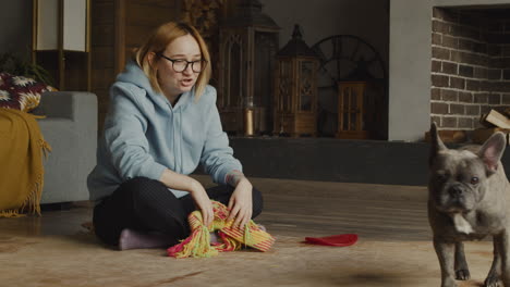 red haired woman playing with her bulldog dog while she is sitting on the floor in the living room at home 1