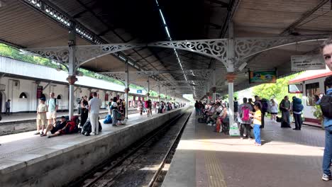 bustling scene at kandy station platform, featuring tourists and locals waiting for a train in sri lanka. the atmosphere is lively with people ready to travel.