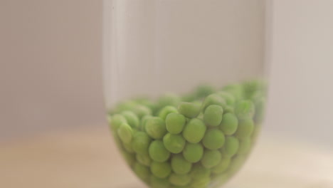 green peas dropping in a still water and shot on 4k and raw with cine style on a white background