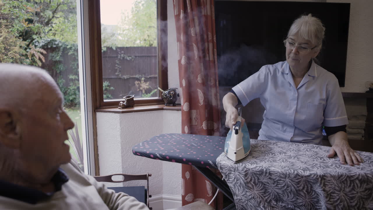 Caregiver ironing for an elderly man
