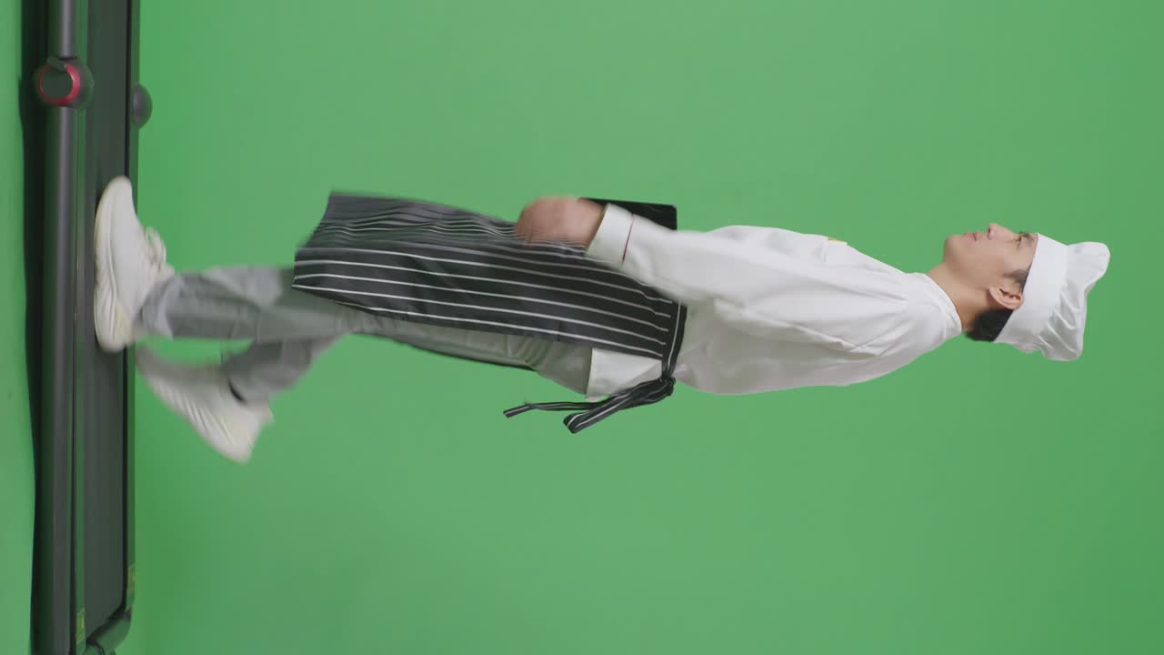 녹색 스크린 배경 스튜디오에서 트레드밀을 는 동안 태블릿을 들고 있는 아시아 남성 요리사