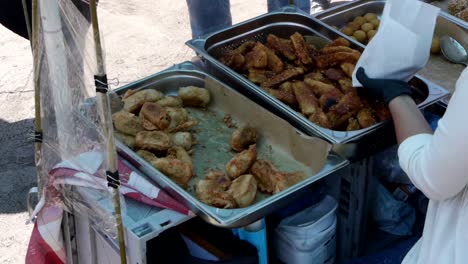 Medium-high-angle-shot-from-the-back-of-a-Korean-street-food-cart-with-the-vendor-filling-a-paper-bag-of-delicacies,-In-Berlin,-Germany