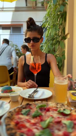 woman enjoying a pizza and aperol spritz outdoors