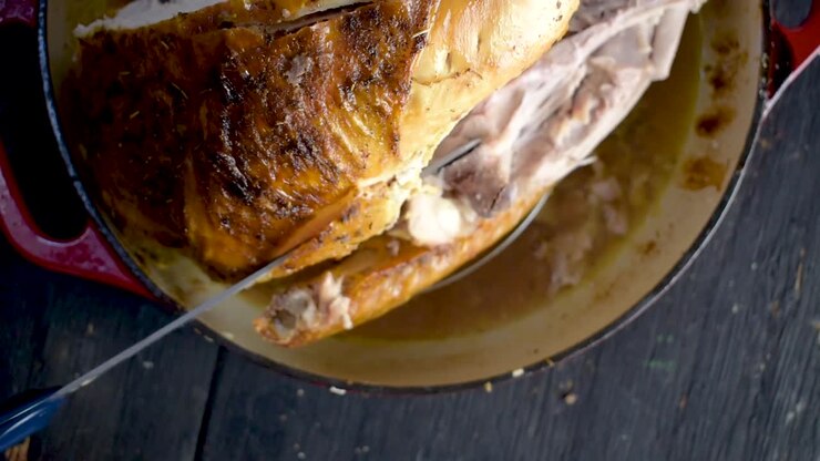 intagliare il tacchino intero al forno con erbe aromatiche con vista dall'alto del coltello elettrico