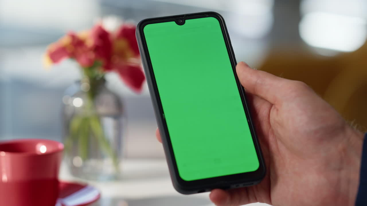 User hand holding mockup smartphone at cozy restaurant closeup. Manager online