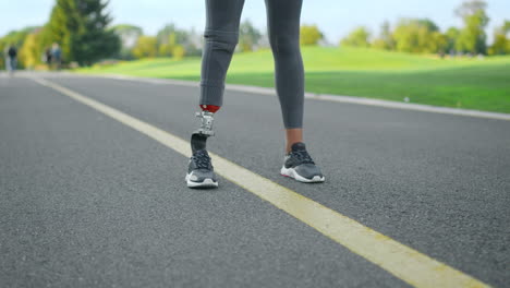 Frau-Mit-Beinprothese-Steht-Auf-Der-Straße.-Sportlerbeine-Bereiten-Sich-Auf-Den-Lauf-Im-Park-Vor