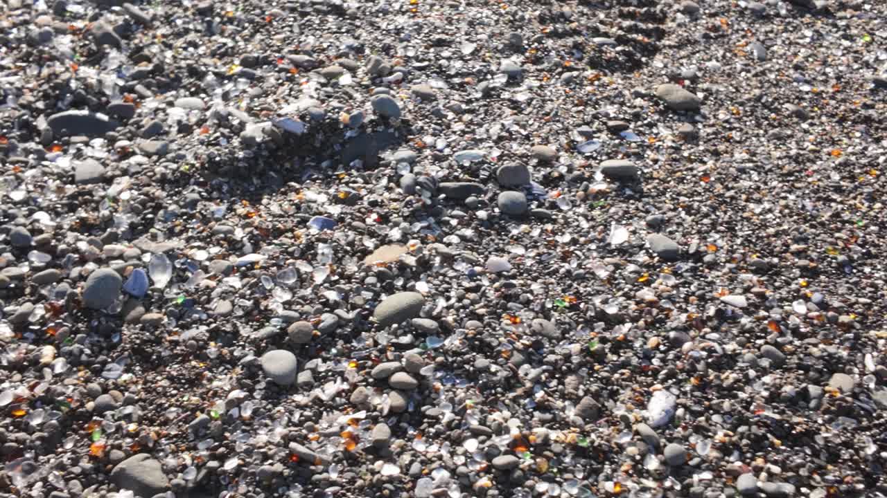 Gimbal close-up panning shot of glass fragments amongst the sand at Glass Beach in Fort Bragg, California. 4K