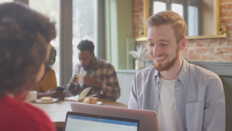 Pareja-De-Negocios-Con-Computadoras-Portátiles-Reuniéndose-Y-Trabajando-Juntos-En-Una-Cafetería