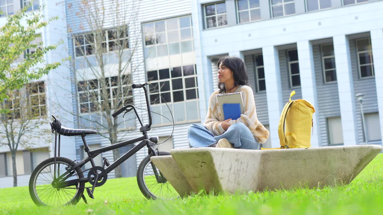 Student on campus with bicycle and backpack