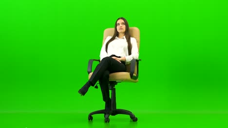 the woman sitting on the office chair on the green background