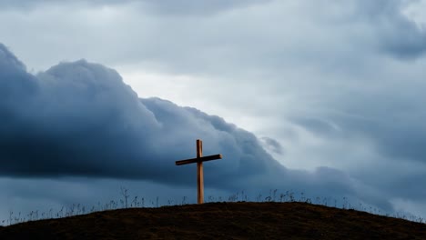 wooden cross on a hill under stormy sky