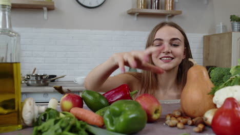 una joven encantadora espiando debajo de la mesa y agarrando una manzana fresca y comiéndola.