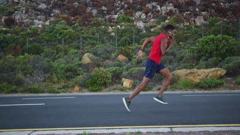 african american man wearing earphones running on the road