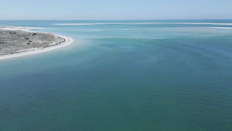 Aerial-panning-shot-showing-turquoise-ocean-and-Troia-Island-during-sunny-day-in-Portugal