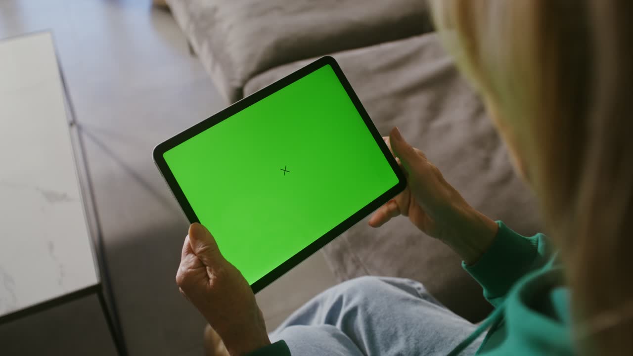 mujer sosteniendo una tableta con pantalla verde