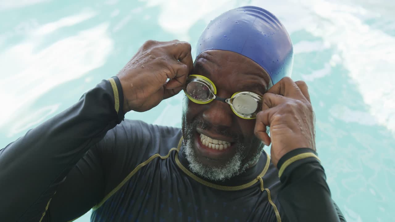 Video of happy senior african american men swimming in pool
