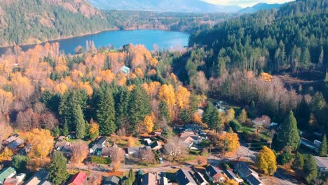 drone shot of small town with lake and mountains in background in the fall